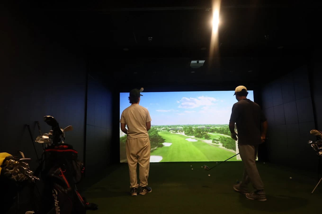 Friends playing in a VIP TrackMan indoor golf simulator bay at Forged Golf